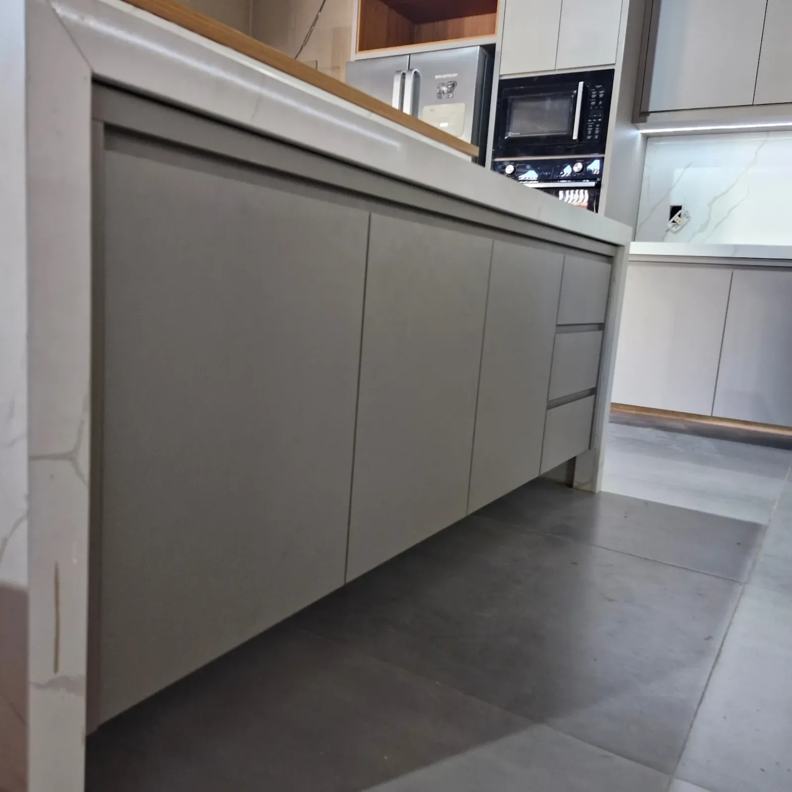 Cozinha planejada com bancada de porcelanato, torre quente e adega, marcenaria Ewald
