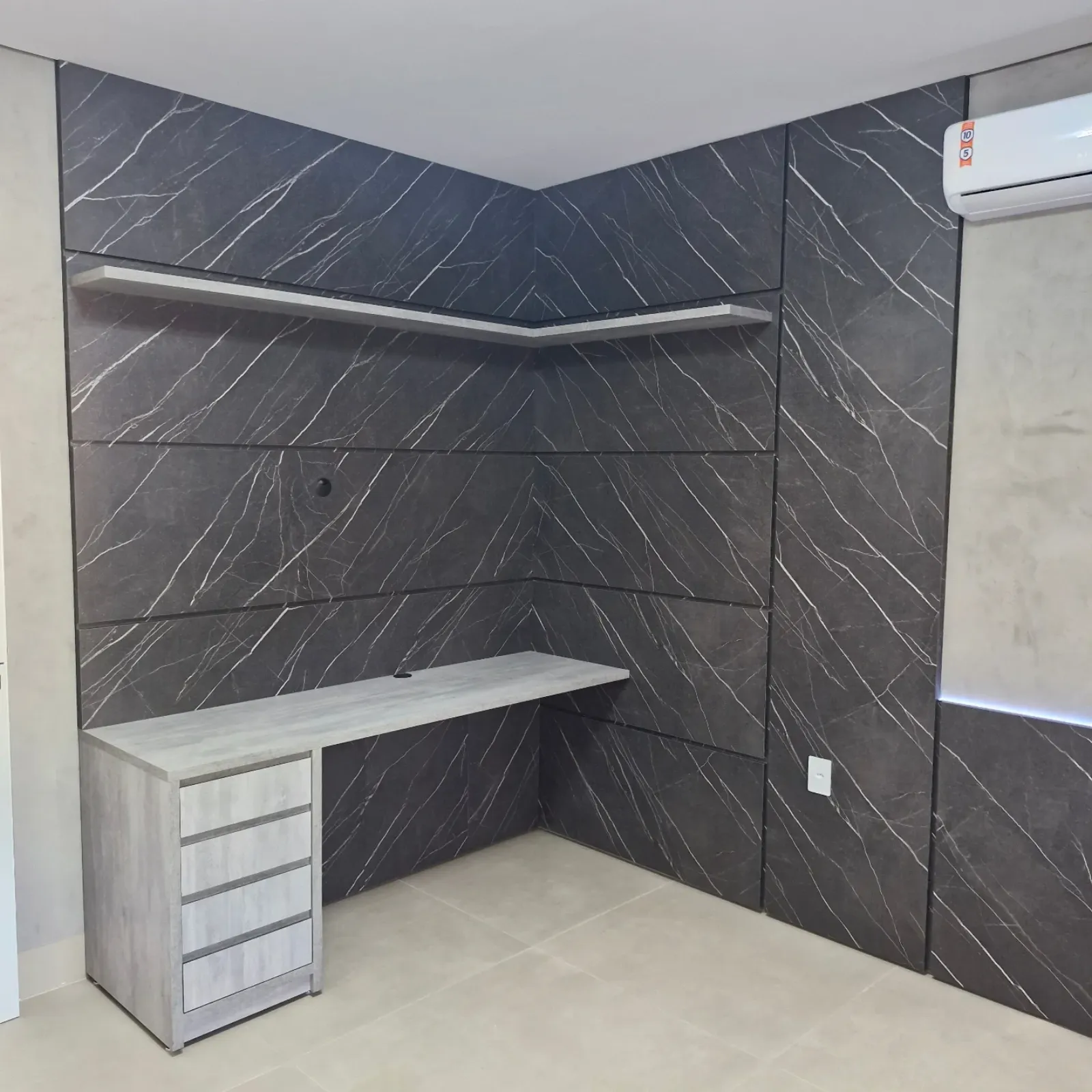 Escrivaninha planejada em quarto com painel marmorizado e prateleira sob medida